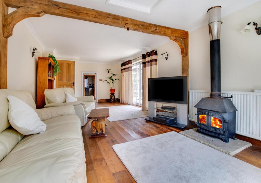 a living room with a couch and a fireplace at 2 Benhall Green in Saxmundham