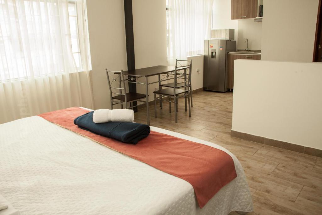 a bedroom with a bed and a kitchen with a table at ApartaSuites Bogota Toscana in Bogotá