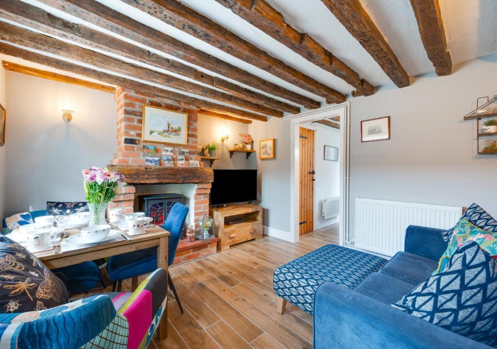 a living room with blue furniture and a fireplace at Puddingmoor Cottage in Beccles