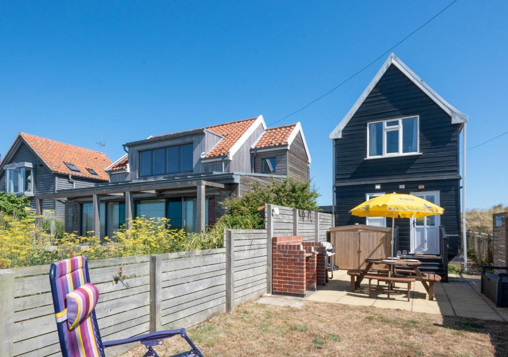 a house with a fence and a table and an umbrella at Beach House in Southwold