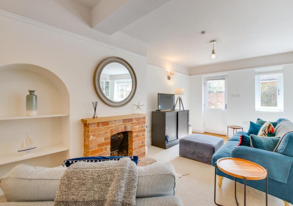 ein Wohnzimmer mit einem blauen Sofa und einem Kamin in der Unterkunft Flat 1 Eversley Cottage in Southwold