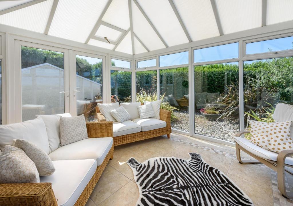 a conservatory with a couch and chairs and windows at Bryn in Abersoch
