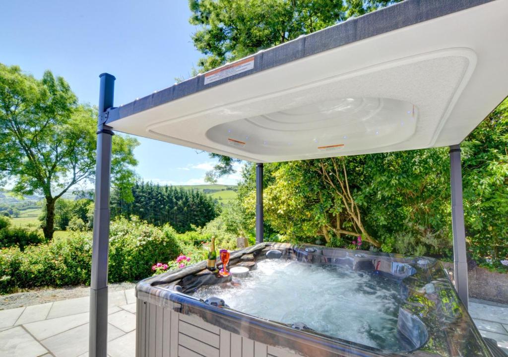 een hot tub in de openlucht op een patio met een luifel bij Bryncylla in Llangurig