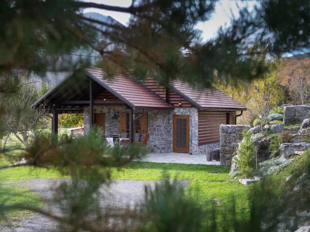 a log cabin with a porch in a garden at Kuca Dide Juke pod Lipovcem in Gospić