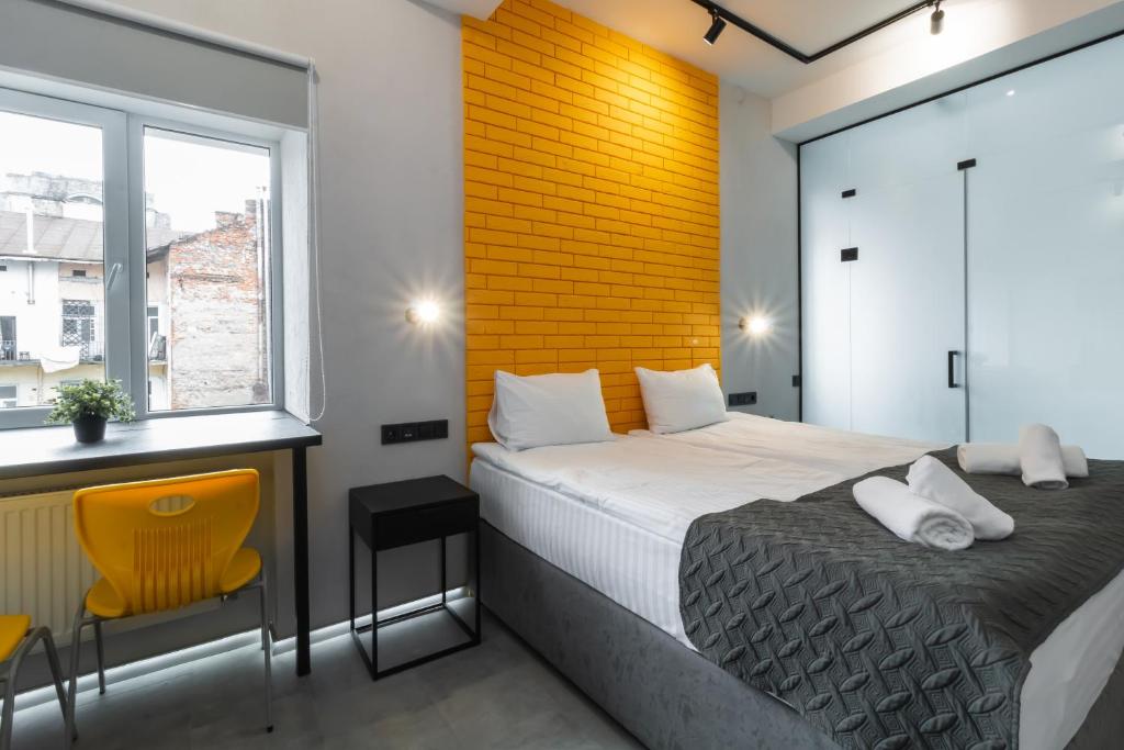 sypialnia z łóżkiem i żółtą ceglaną ścianą w obiekcie Stories Hub w Lwowie