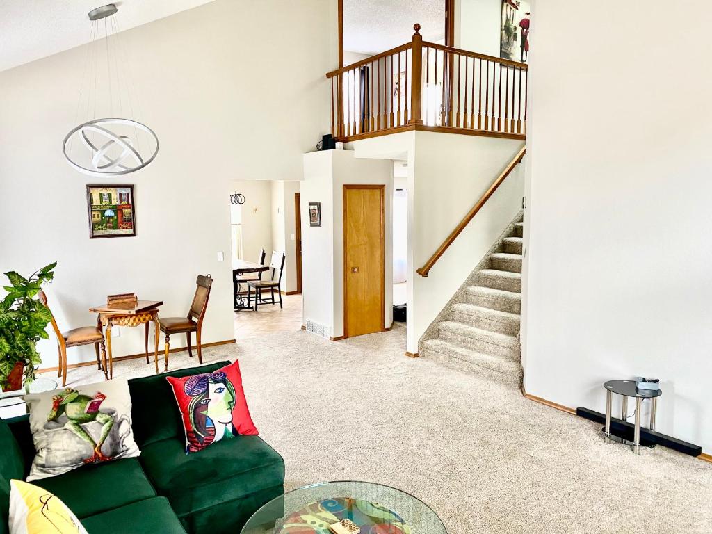 a living room with a green couch and a staircase at Artsy Home close to USAFA with Fireplace and Patio in Colorado Springs