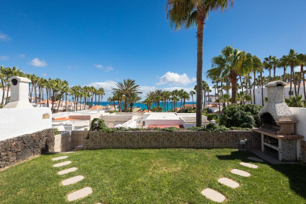 a lawn with palm trees and the ocean in the background at Casa Silvia, casa con jardín y vista al mar in Costa Calma