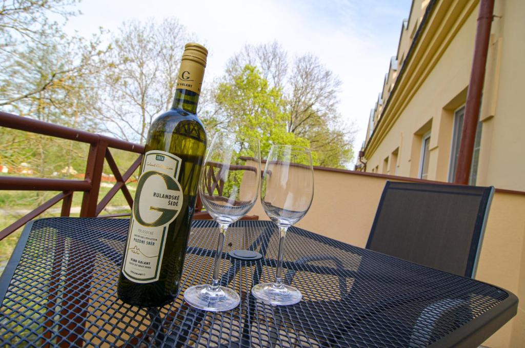 a bottle of wine and two wine glasses on a table at Hotel Galant Lednice in Lednice