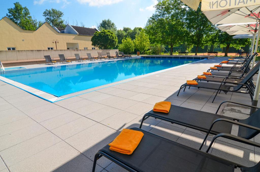 a swimming pool with chairs and an umbrella at Hotel Galant Lednice in Lednice