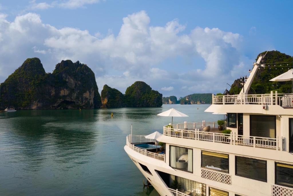 un bateau sur l'eau avec des montagnes en arrière-plan dans l'établissement Hermes Cruises, à Hạ Long