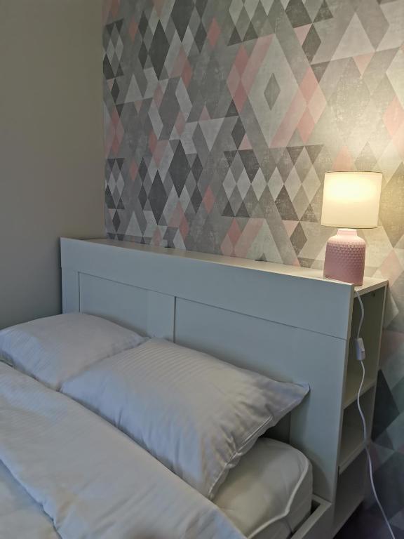 a bedroom with a bed and a lamp on a wall at Apartament Manhattan in Kłodzko