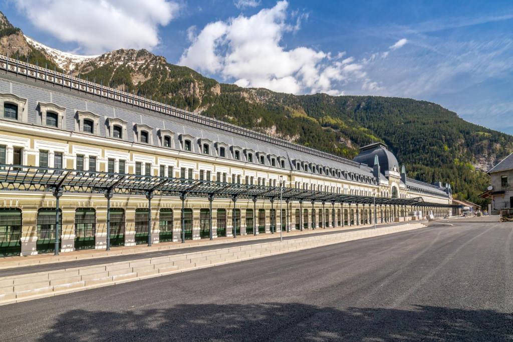 a large white building with a mountain in the background at Canfranc Estación, a Royal Hideaway Hotel - Gran Lujo in Canfranc-Estación