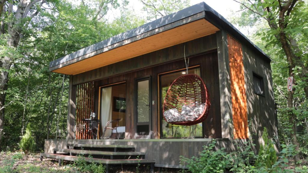 una pequeña casa en el bosque con un columpio en Shavit Village Glamping, en Akhatani