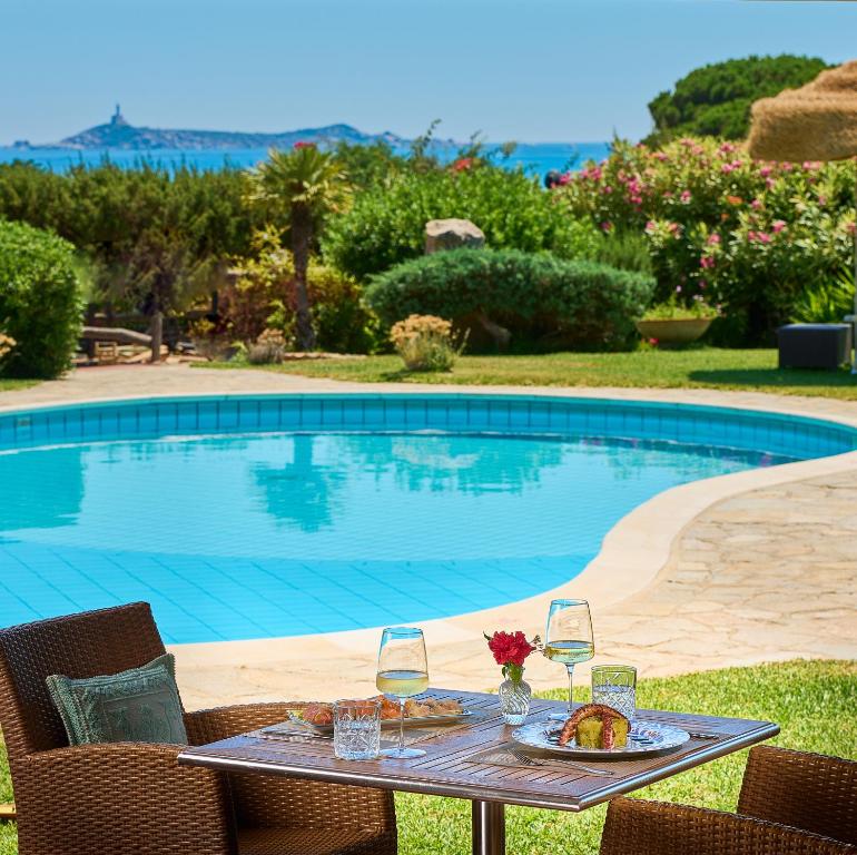 stół z kieliszkami do wina obok basenu w obiekcie Residence Le Bouganville w mieście Villasimius