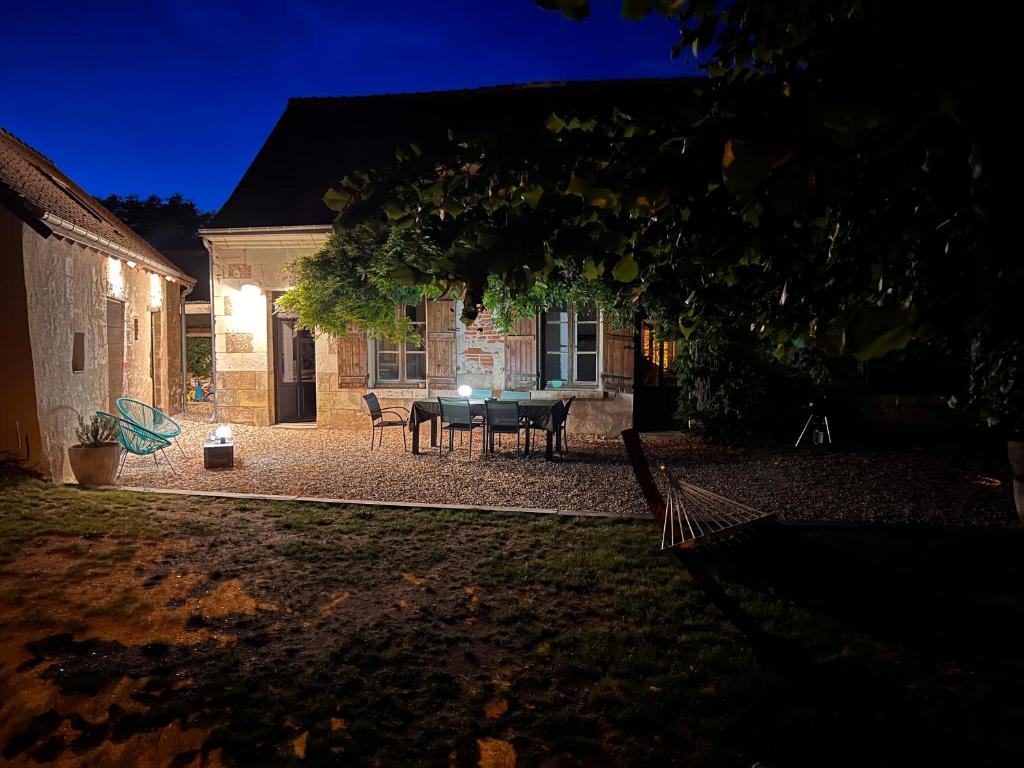 a patio with a table and chairs in a yard at night at La Maison de Frédéric in Francueil