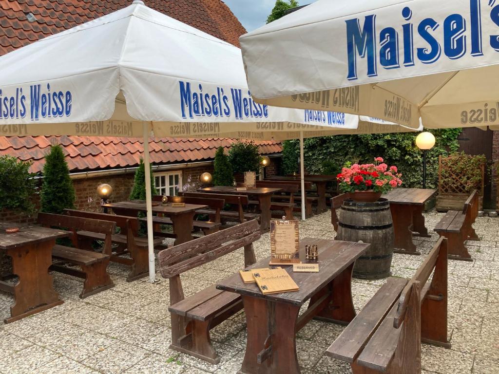 un restaurante con mesas de madera y sombrillas en Restaurant- Hotel- Biergarten Haduloha en Otterndorf