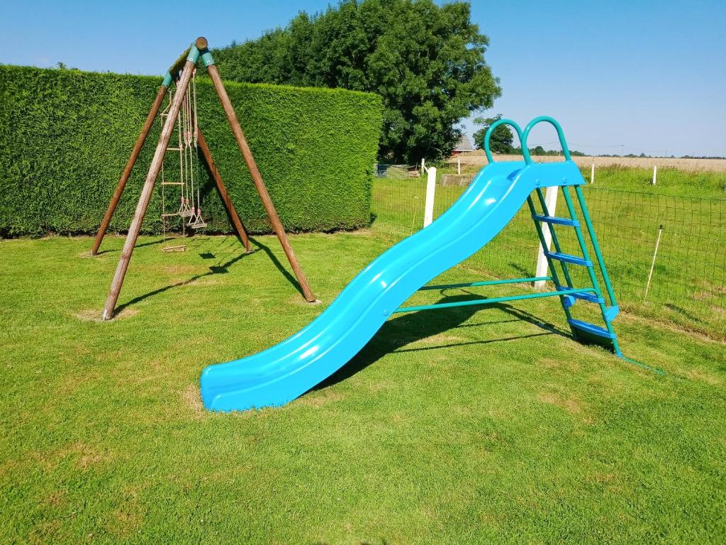 a playground with a blue slide on the grass at Maison de 2 chambres avec jardin clos et wifi a Epreville en Lieuvin in Épreville-en-Lieuvin