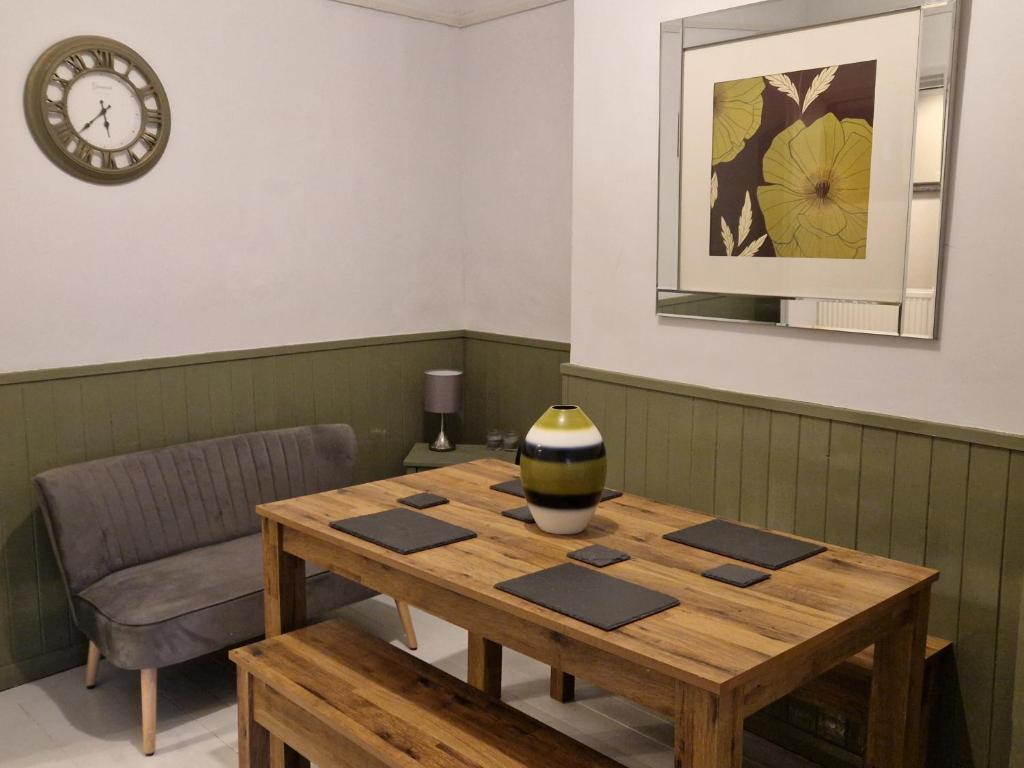 a wooden table in a room with a clock on the wall at Three Bedroomed House in Morecambe in Morecambe