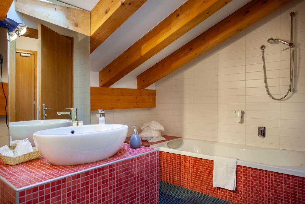 łazienka z dużą białą wanną i umywalką w obiekcie Hotel Romanda w mieście Levico Terme