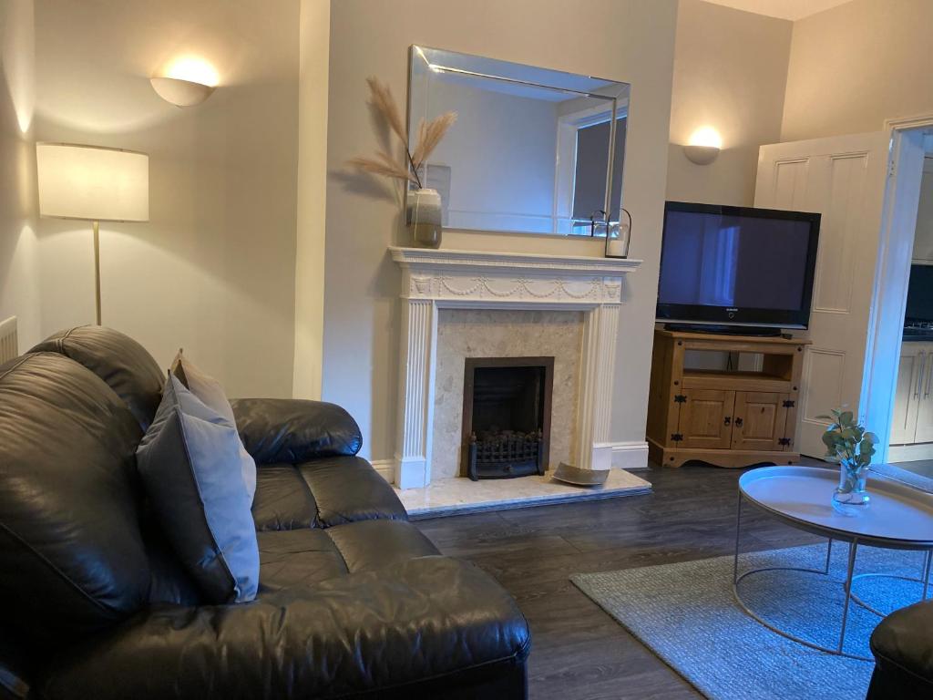 uma sala de estar com um sofá de couro e uma lareira em Alexander Apartments Jesmond em Newcastle upon Tyne