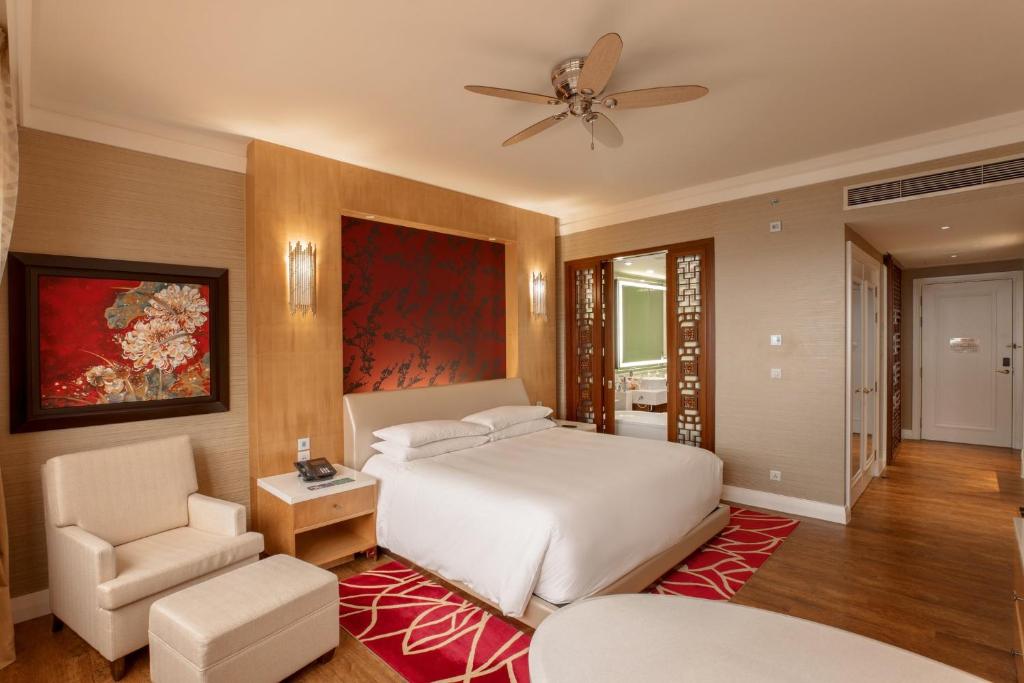 a bedroom with a white bed and a chair at InterContinental Grand Ho Tram in Ho Tram