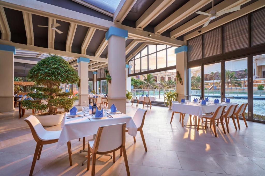 a restaurant with white tables and chairs and a pool at InterContinental Grand Ho Tram in Ho Tram
