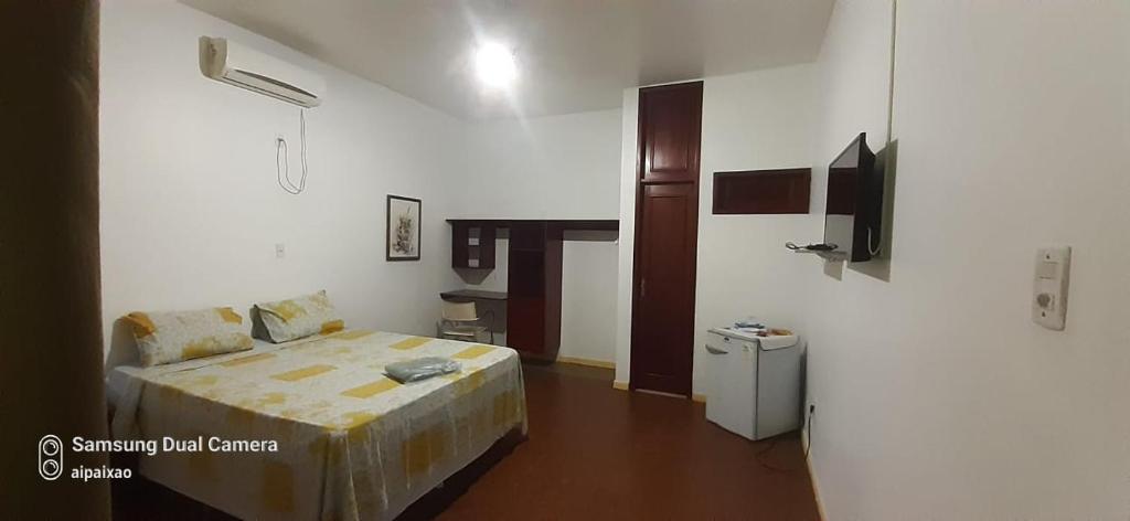 a small bedroom with a bed and a small refrigerator at Garden Hotel e Eventos in Benevides
