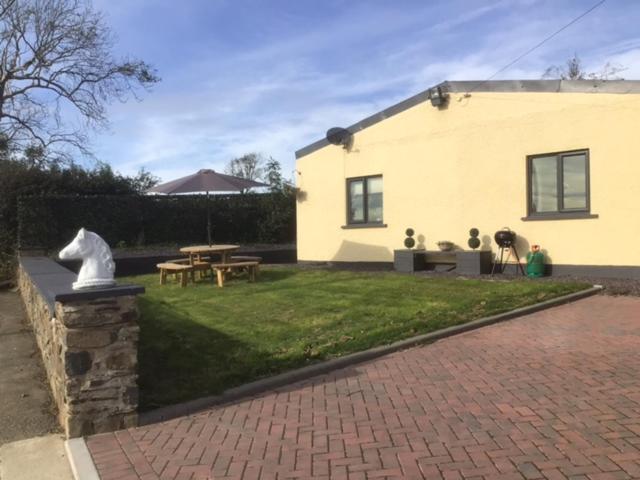 a house with a brick yard with a picnic table at Letterston Valley View in Haverfordwest