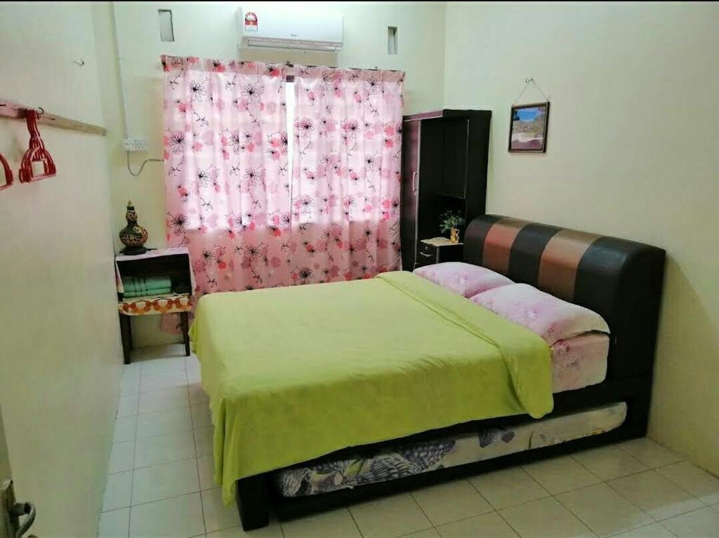 a bedroom with a bed and a pink curtain at Heawood Homestay Sungai Siput in Sungai Siput