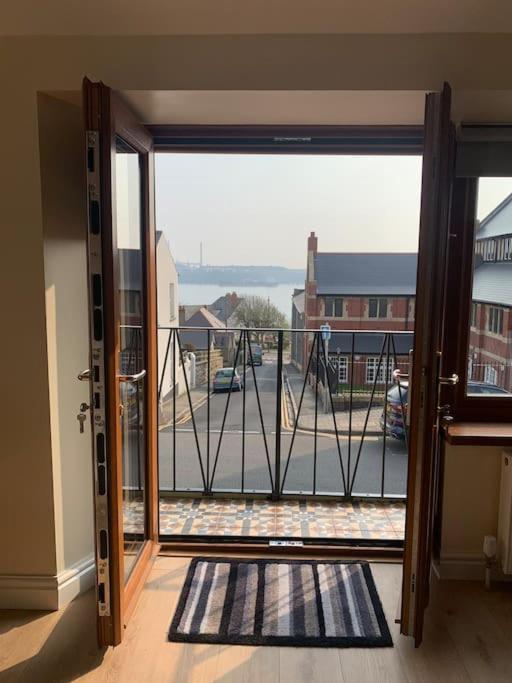 una porta aperta su un balcone con vista su un parco giochi di Kennys apartment a Milford Haven