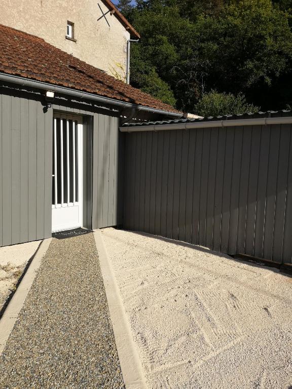 un garage con una porta bianca e una recinzione di moulin de ROUCHILLOU a Saint-Martial-de-Valette
