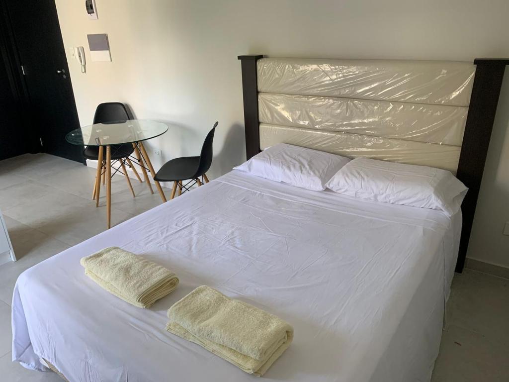 1 dormitorio con 1 cama blanca y 2 toallas en Depto en Asuncion- excelente ubicación- Villa Morra #402, en Asunción