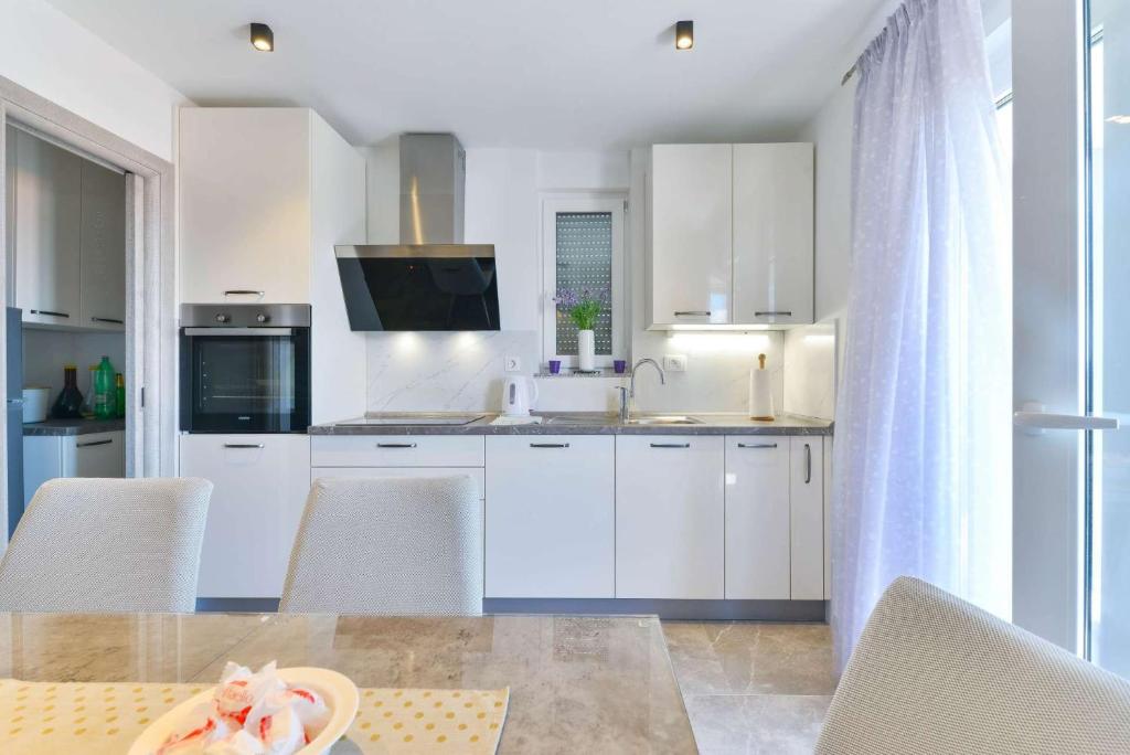 kuchnia z białymi szafkami i stołem z krzesłami w obiekcie Modern Villa Futura with pool w mieście Maslenica