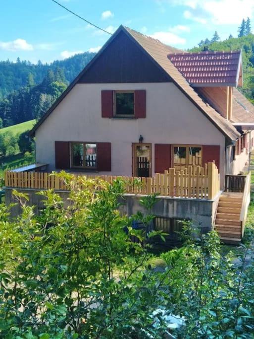une maison avec une terrasse couverte et une clôture devant elle dans l'établissement L'Estive, gîte à la ferme en montagne, à Eschbach-au-Val
