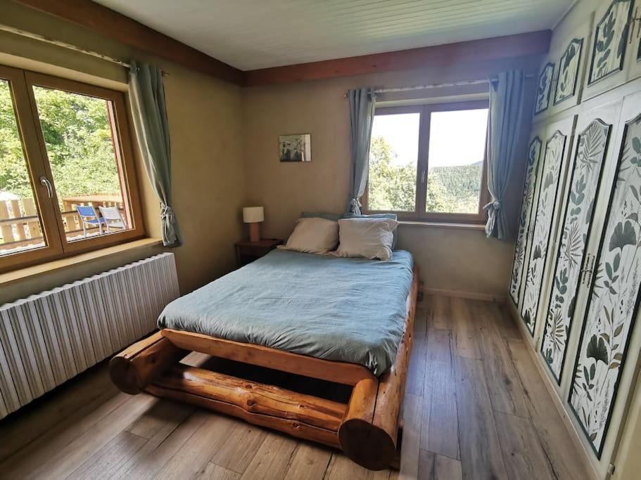 um quarto com uma cama de madeira num quarto com uma janela em L'Estive, gîte à la ferme en montagne em Eschbach-au-Val