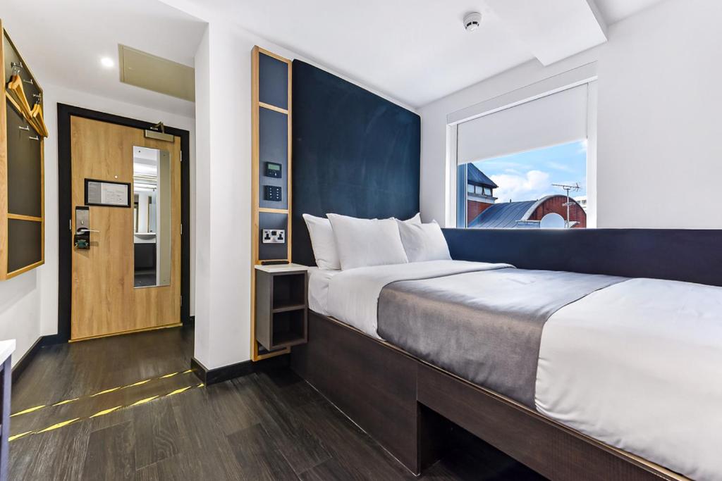 a bedroom with a large bed and a large window at The Z Hotel Strand in London