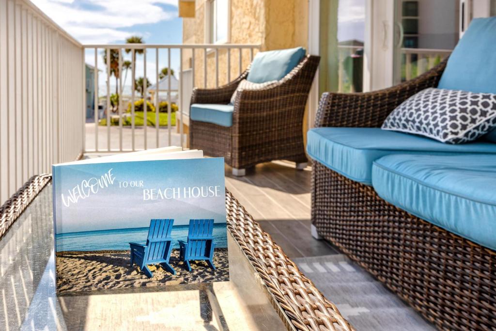 清水海灘的住宿－#1 Stunning Ocean View completely remodeled luxury condo with huge balcony，一个带柳条椅的门廊和阅读海滨别墅的标志