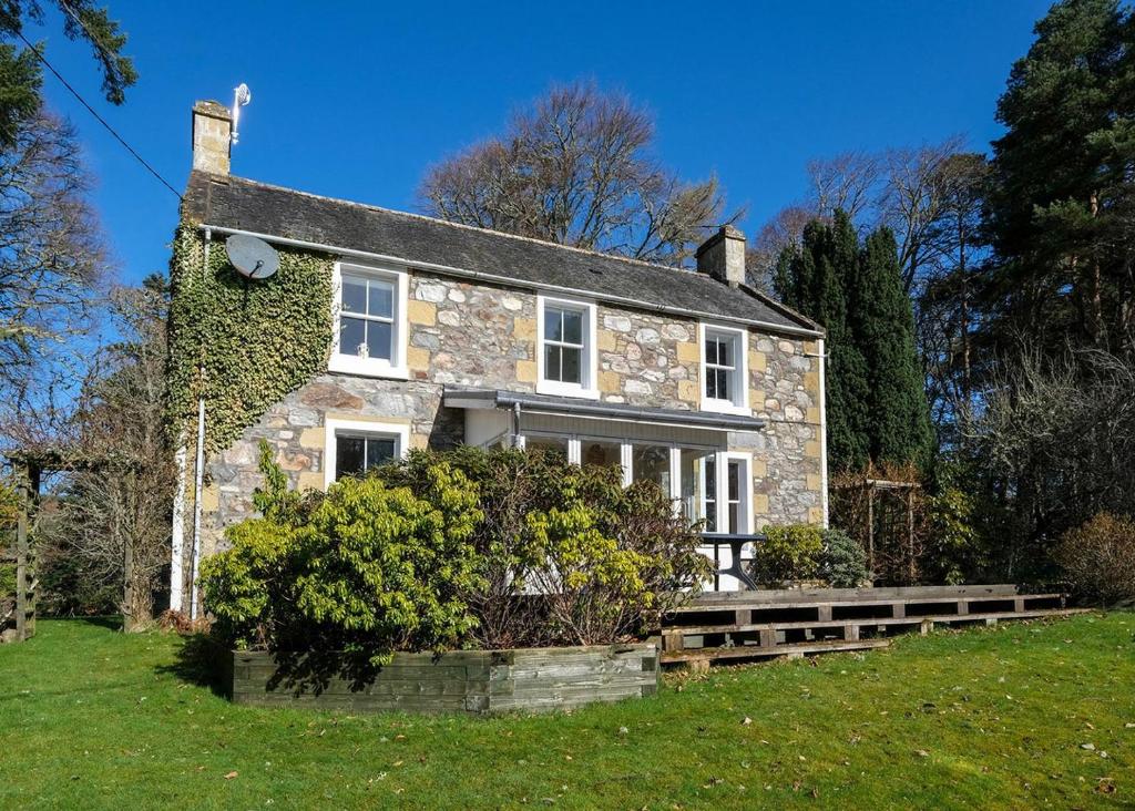 a stone house with ivy on the side of it at Gledfield Highland Estate in Culrain