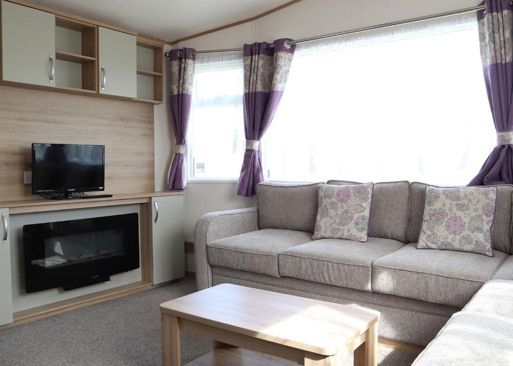 a living room with a couch and a tv at Coastfields Holiday Village in Ingoldmells