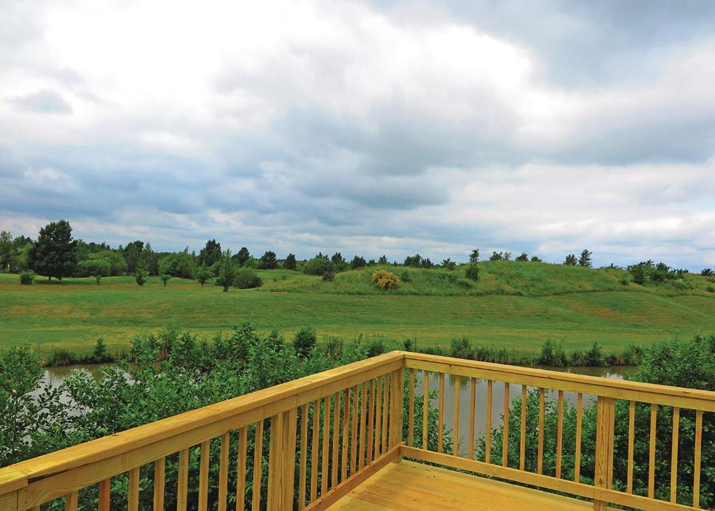 een houten terras met uitzicht op een veld bij Kingswood Golf Lodges in Thorne