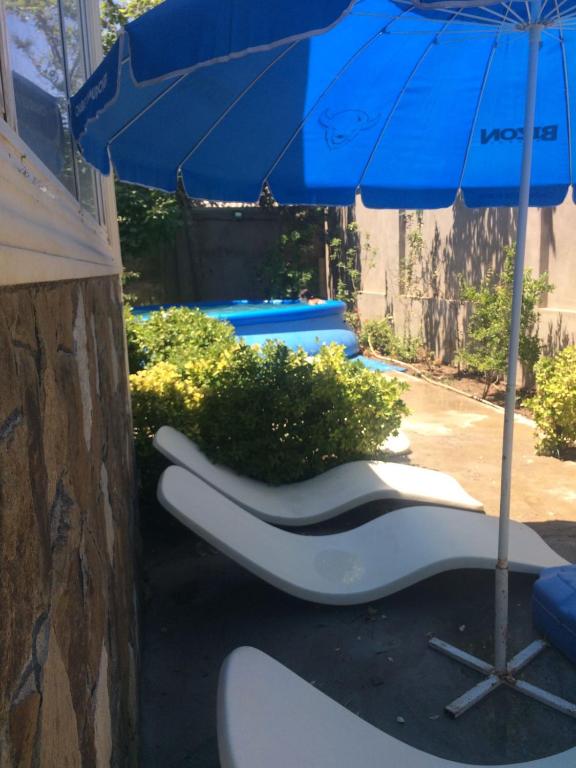 a blue umbrella and a pair of white chairs and an umbrella at дом в новханах у моря in Baku