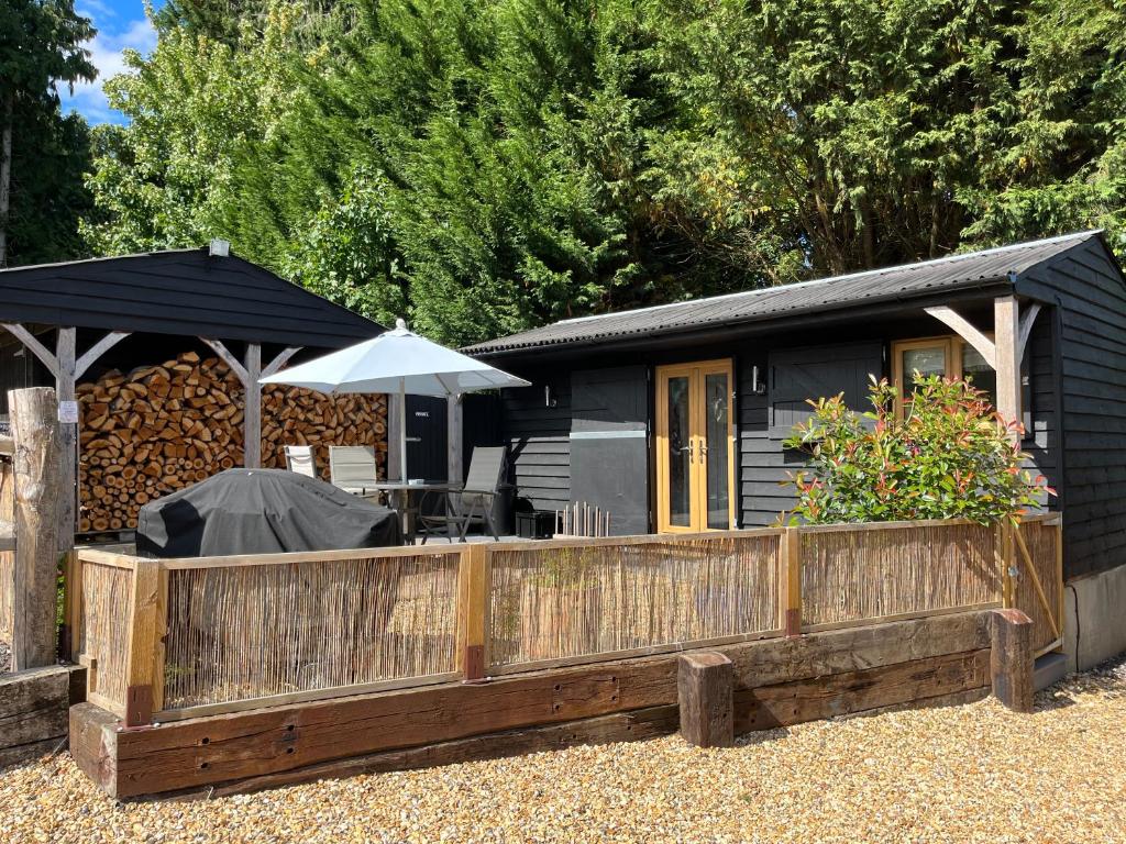 a small cabin with a fence and an umbrella at Hascombe Accommodation in Hascombe