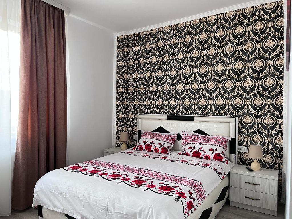 a bedroom with a bed with red pillows and a wallpaper at Casa Cojocaru in Cârcea