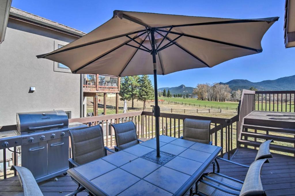einen Tisch mit einem Sonnenschirm auf einer Terrasse mit einem Grill in der Unterkunft Family-Friendly Home with Hot Tub 1 Mi to Dtwn in Estes Park