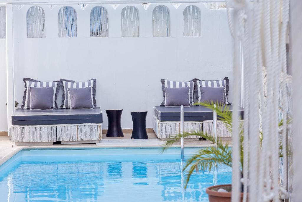 a swimming pool in a room with two chairs next to a house at Loizos Stylish Residences in Fira