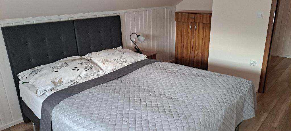 a bed with a black headboard in a bedroom at Domek całoroczny Nad Stawem in Powidz