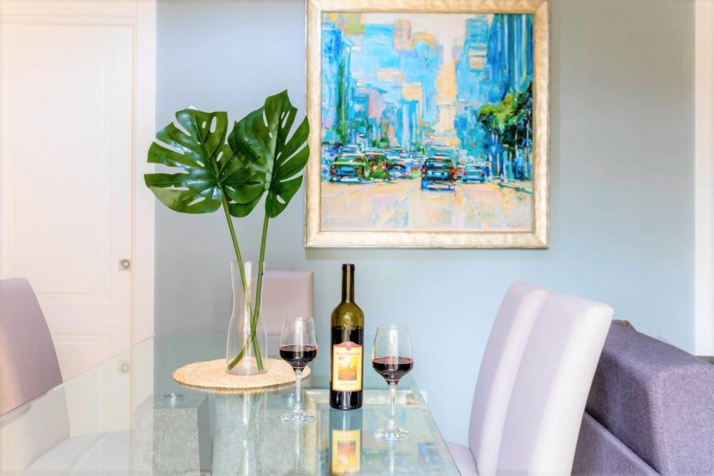 a glass table with two glasses of wine and a plant at Hostly - Art & Color Rome Midtown - 3BR 2BA in Rome