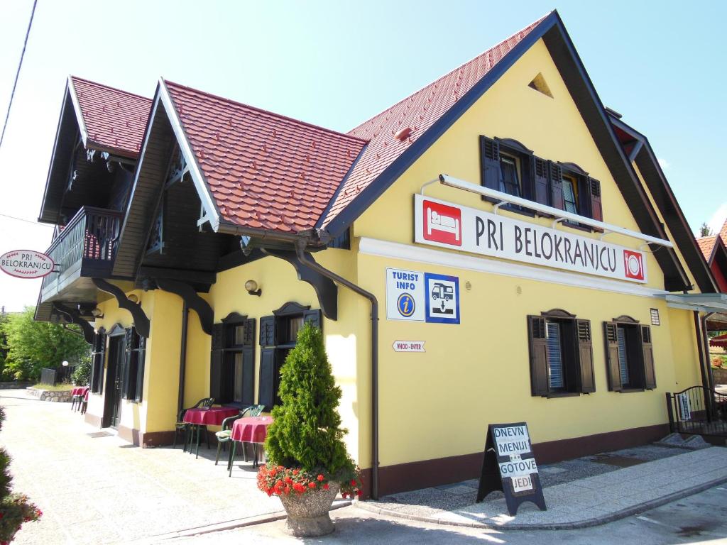 un edificio amarillo con un cartel delante en Hotel Pri Belokranjcu, en Novo Mesto