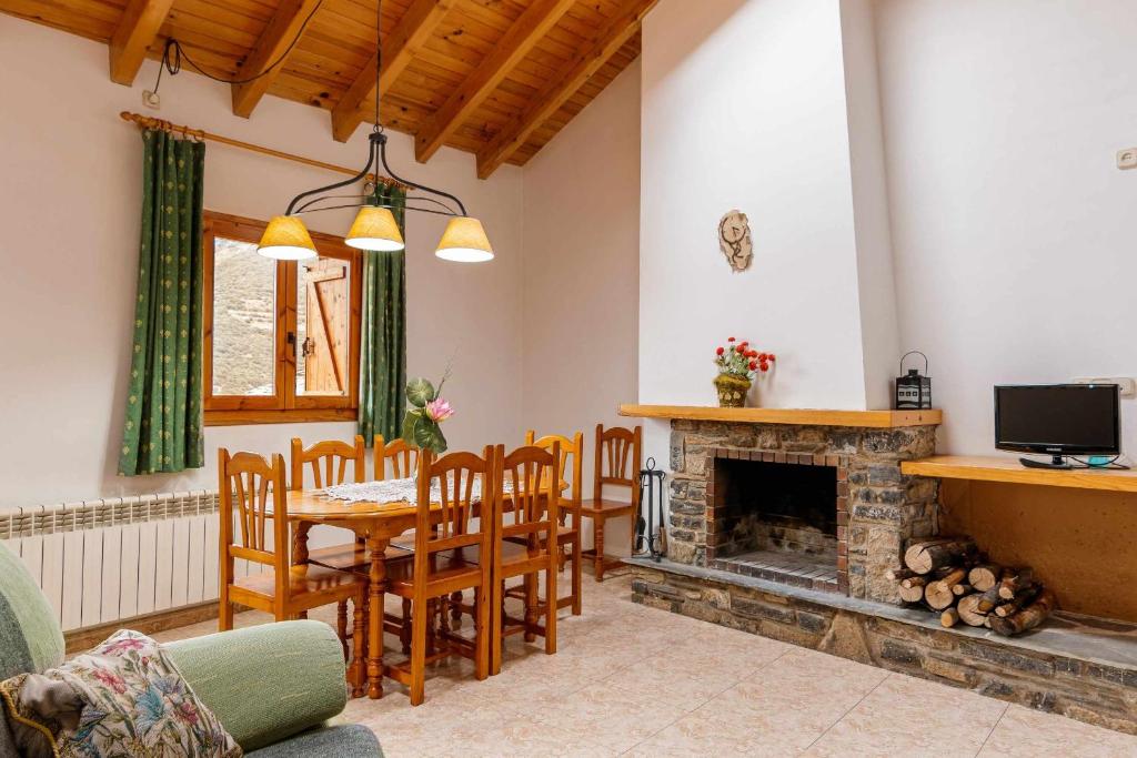 ein Wohnzimmer mit einem Kamin, einem Tisch und Stühlen in der Unterkunft Casa Xaupi 1 in Roní