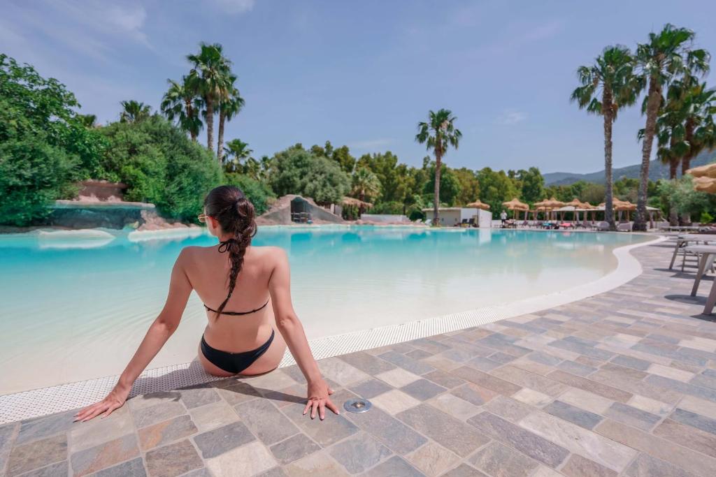 a woman in a bikini sitting next to a swimming pool at Il Monastero in Geremèas